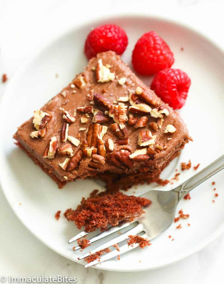 A slice of Texas Sheet Cake with fork and raspberries on the side