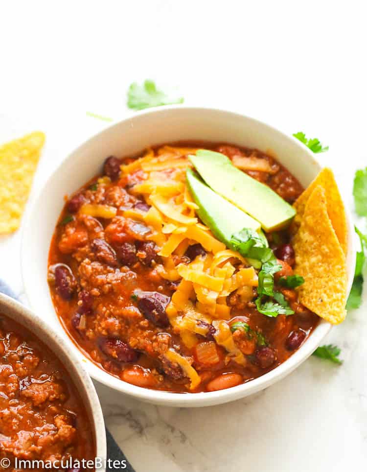 Chili Recipe in a Bowl topped with cheese, avocado, and tortilla chips