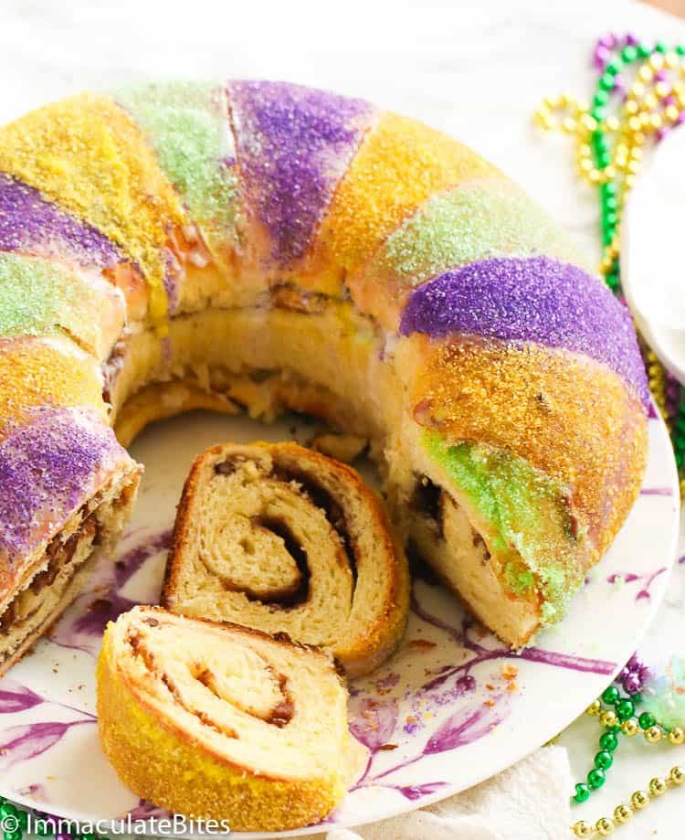 a plate of sliced king cake and some colorful beads in the background