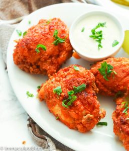 Insanely spicy Nashville Hot Chicken on a white platter and garnished with chopped parsley