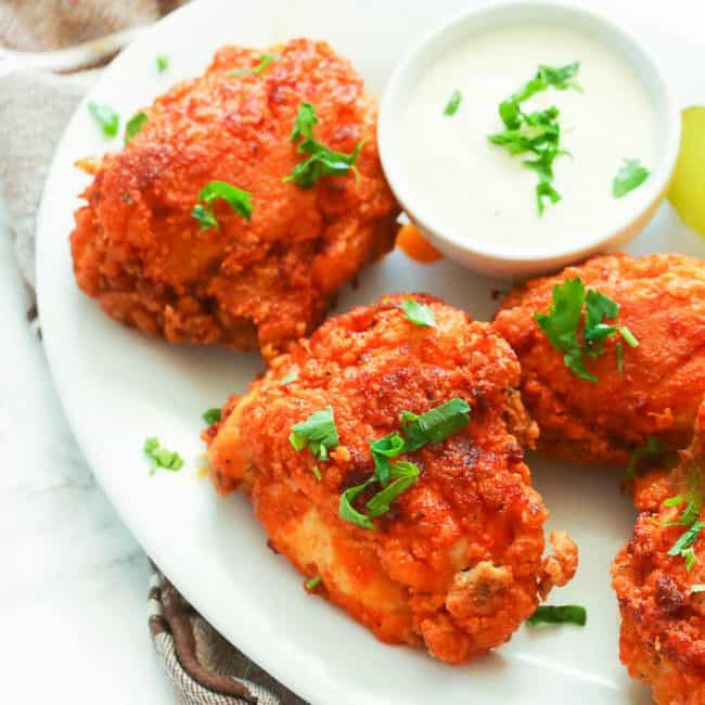 Insanely spicy Nashville Hot Chicken on a white platter and garnished with chopped parsley