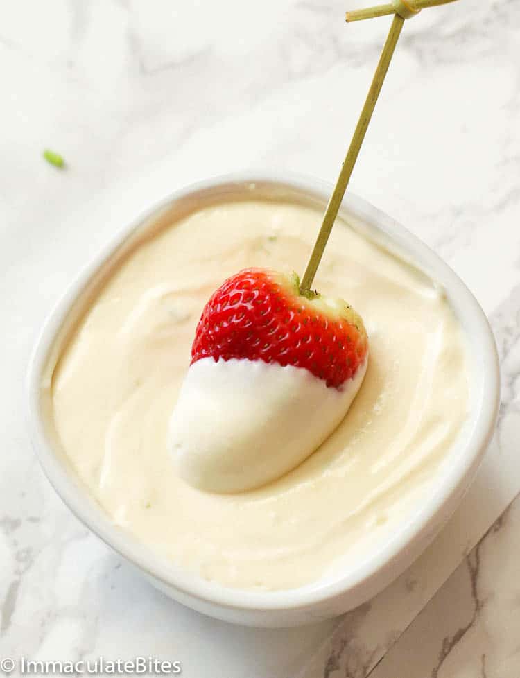 Dipping a fresh strawberry into a bowl of decadent cream cheese fruit dip