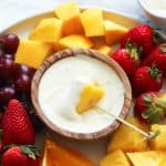 Dipping a pineapple chunk into insanely delicious cream cheese fruit dip