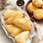 Different types of bread featuring Scones on a white serving bowl with circle scones on a saucer with chocolate sauce