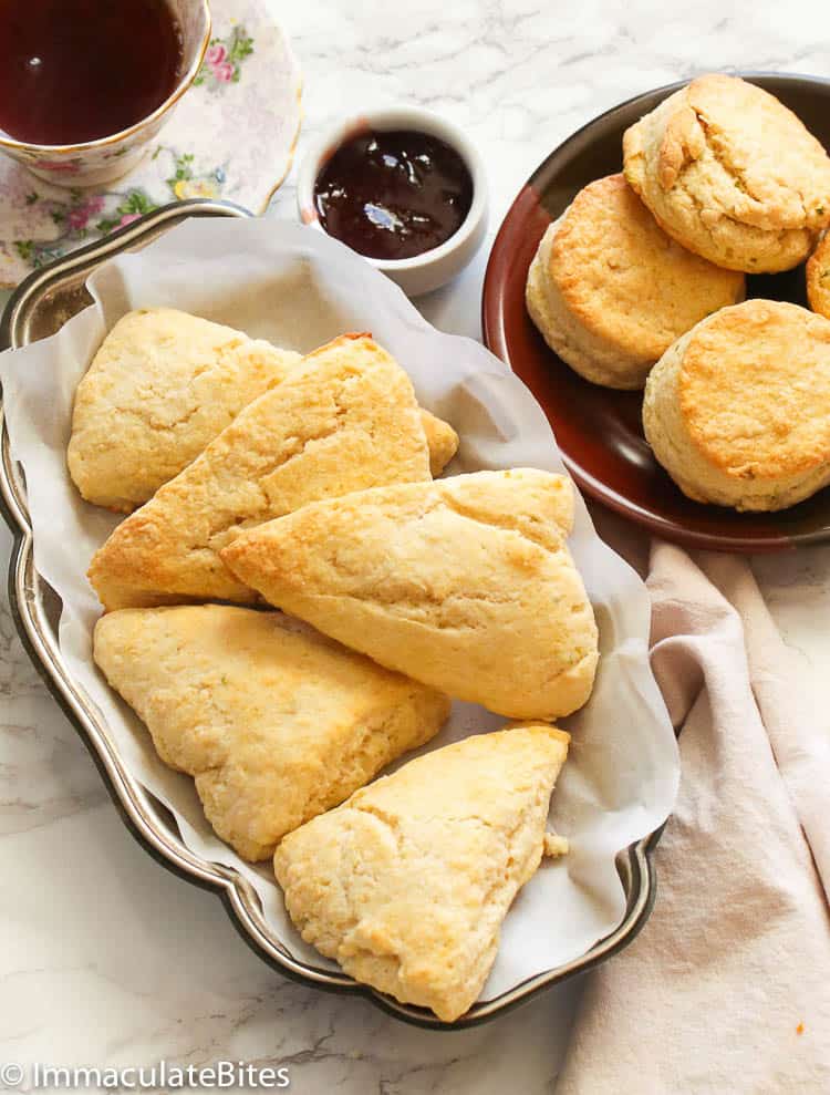Different types of bread featuring Scones on a white serving bowl with circle scones on a saucer with chocolate sauce