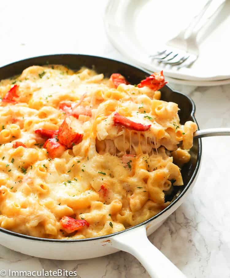 Lobster Mac and Cheese in a skillet with plates and forks in the background