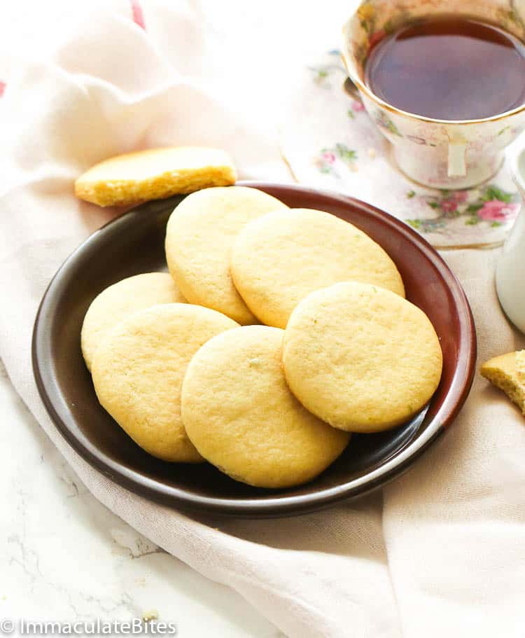 a plate of six tea cakes served with tea in the background