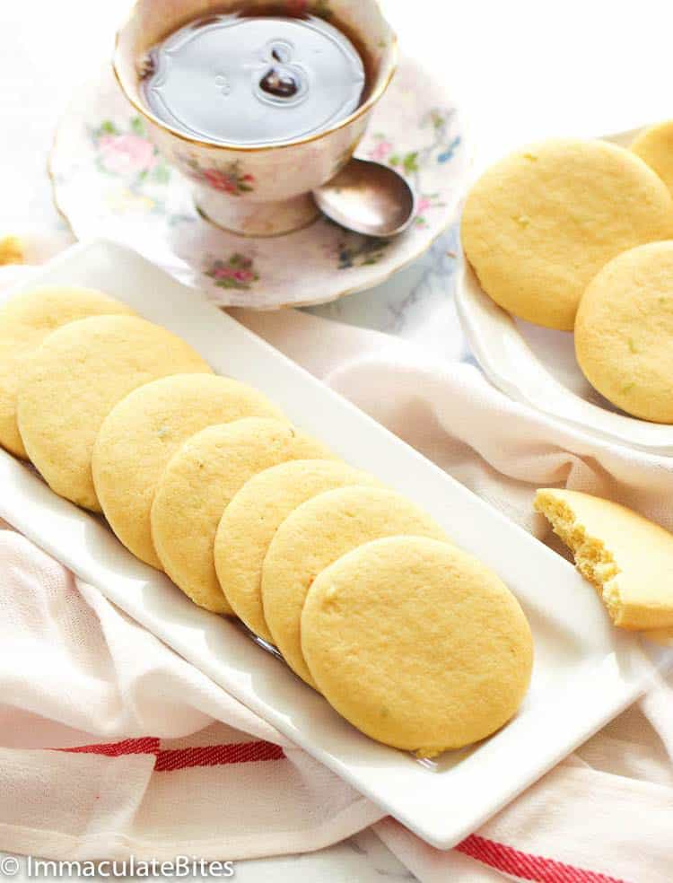 Southern tea cakes on white plates served with hot tea in a porcelain cup.