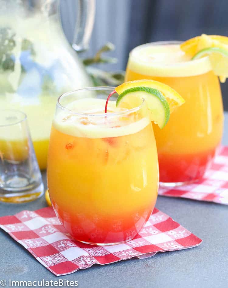 Rum Punch in a stemless wine glass decorated with lime and lemon slices and a cherry