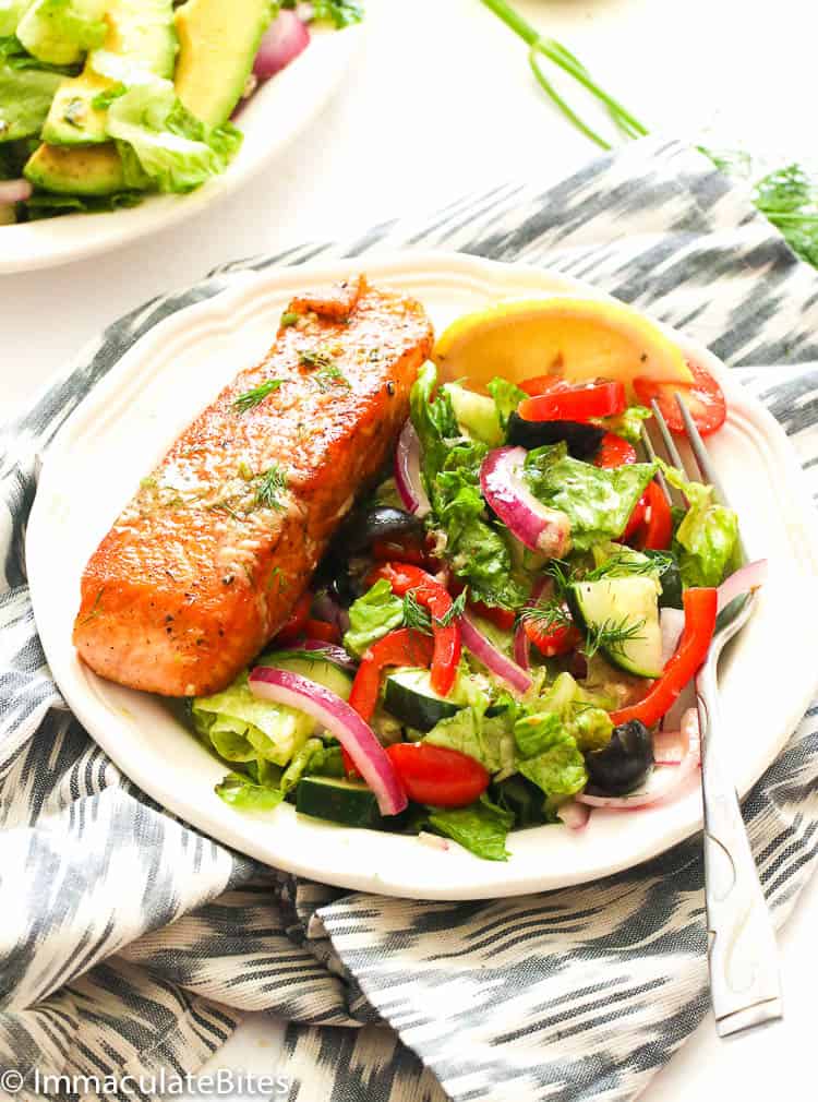 salmon with a refreshing garden salad on a white plate with an amazing herby dressing
