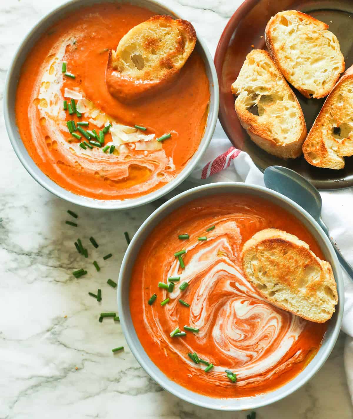 Two bowls of tomato bisque with homemade garlic bread