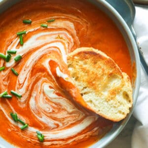 Garlic bread dipped into tomato bisque sprinkled with chives