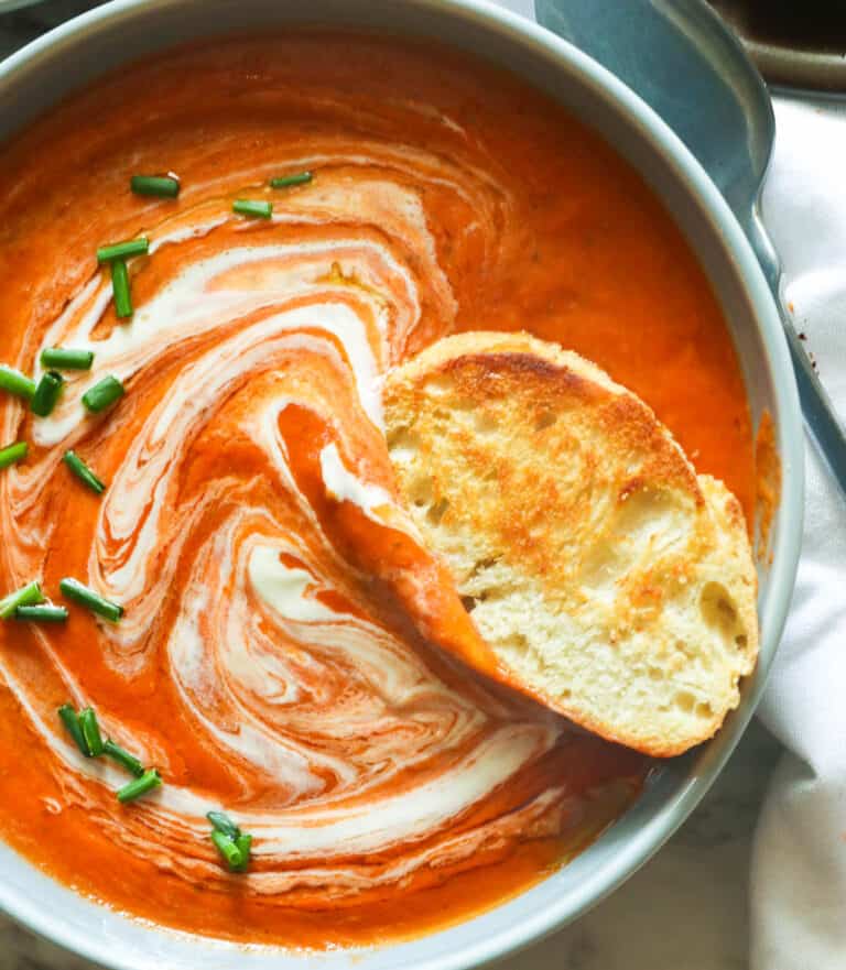 Garlic bread dipped into tomato bisque sprinkled with chives