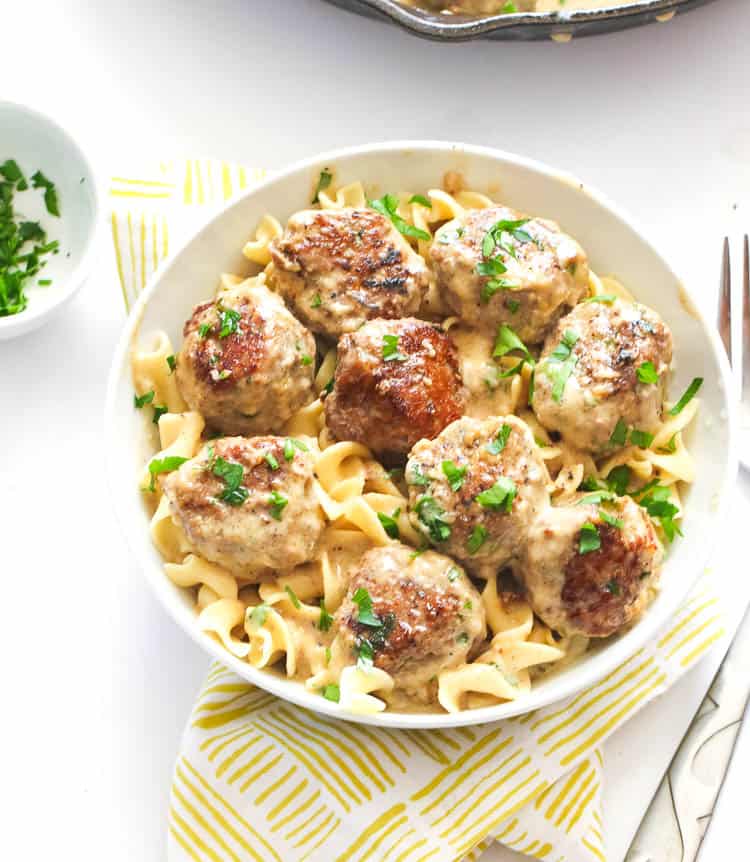 Swedish meatballs in sauce over egg noodles and garnished with fresh parsley