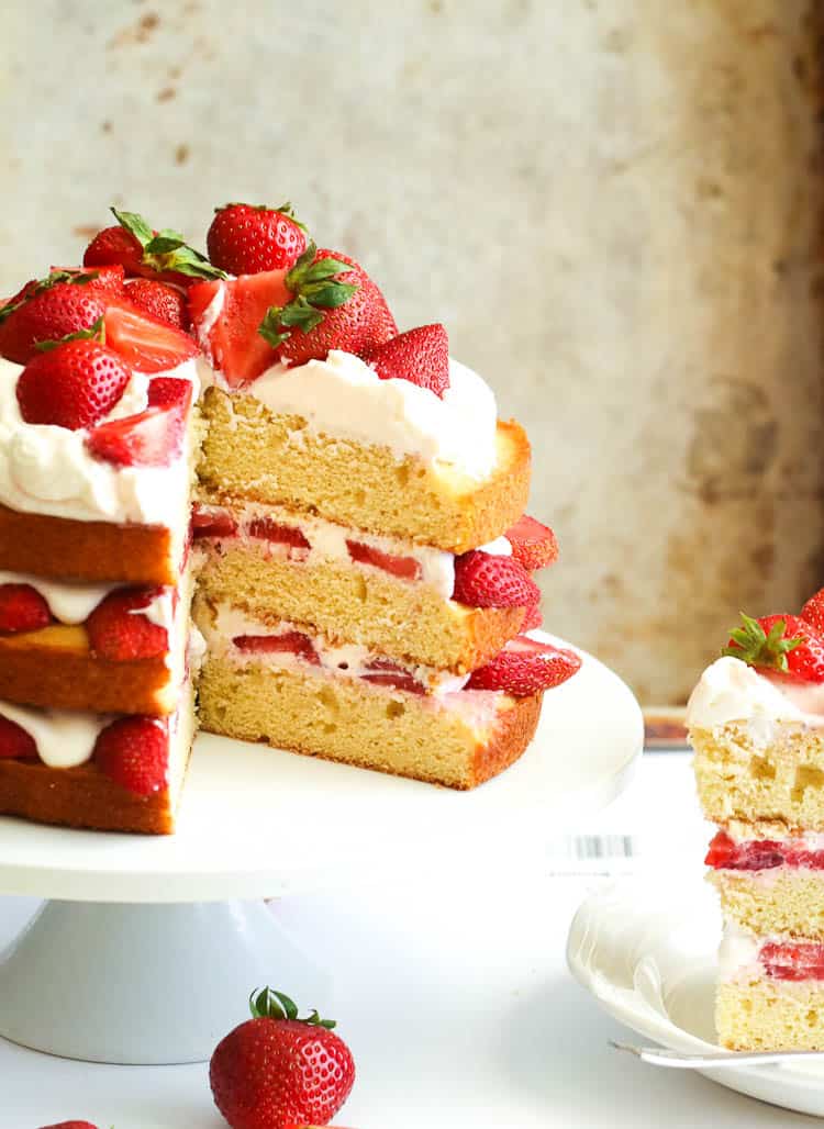 Strawberry Shortcake sliced and ready to serve smothered in decadent whipped cream