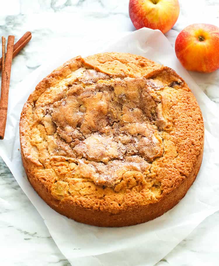 Freshly baked Cinnamon Apple Cake with apples and cinnamon stick in the background