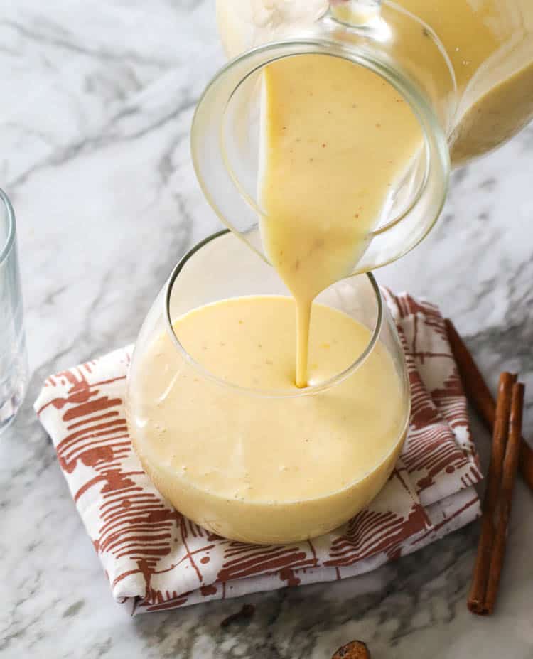 A Pitcher of Homemade Eggnog Being Poured Down to a Glass