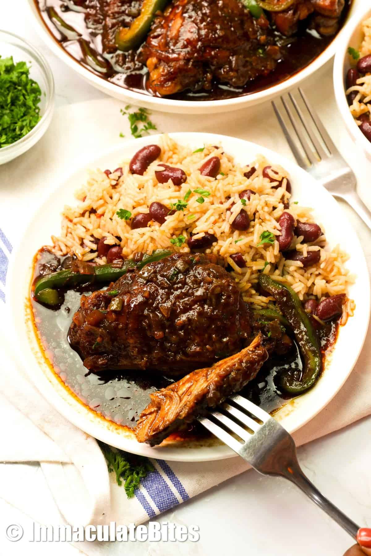 Slicing into tender bite of brown stew chicken