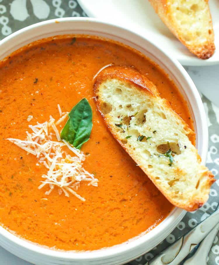 A bowl of tomato basil soup with crusty bread