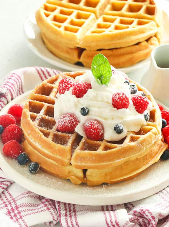 Homemade waffles topped with whipped cream and berries