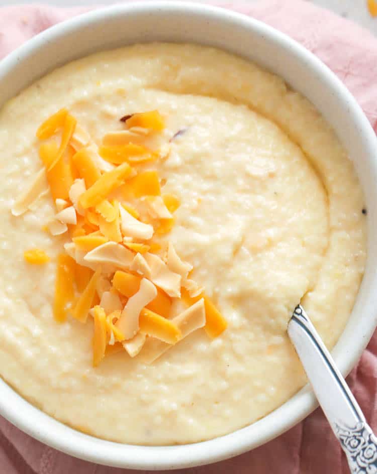 Delicious cheese grits in a white bowl with spoon