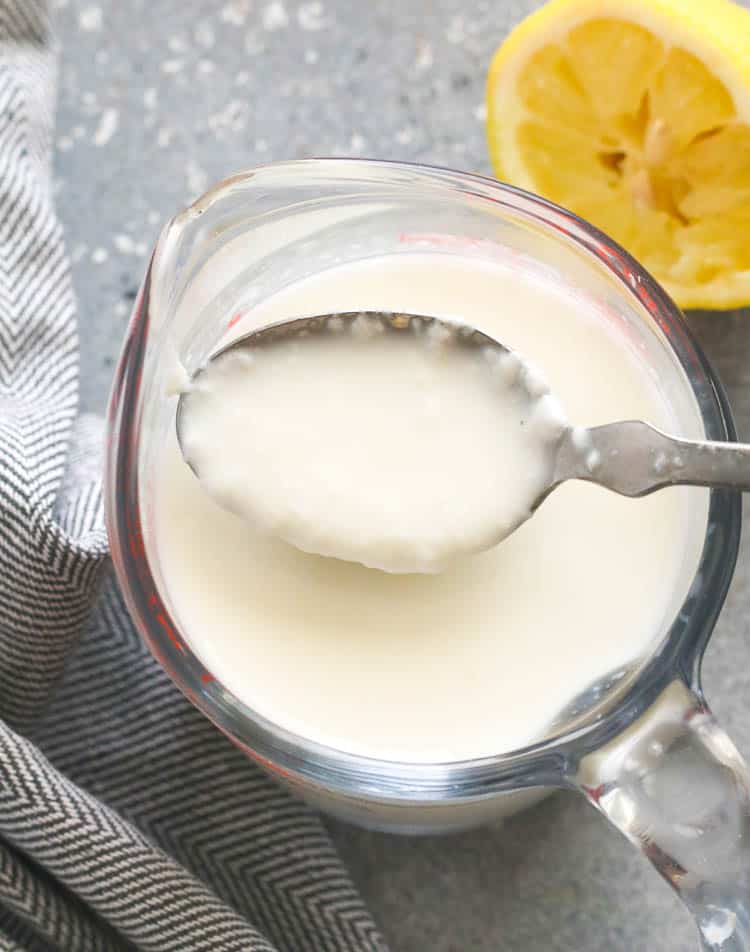 A Glass of Buttermilk with Half-Squeezed Lemon in the Background