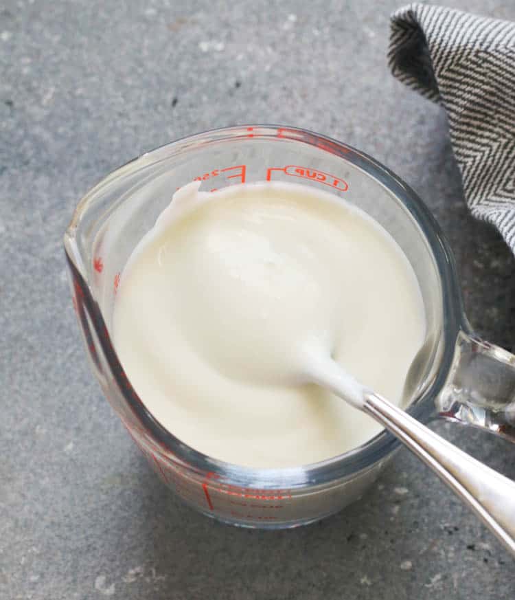 A Pyrex Glass of Buttermilk with a Spoon in it