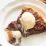 Chocolate and pecans in a pie topped with a scoop of vanilla ice cream.