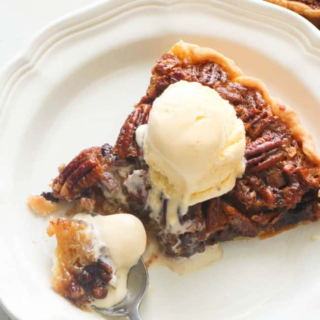 Chocolate and pecans in a pie topped with a scoop of vanilla ice cream.