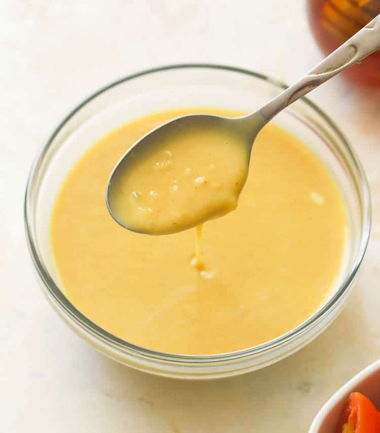 a clear bowl and a teaspoon of honey mustard dressing 