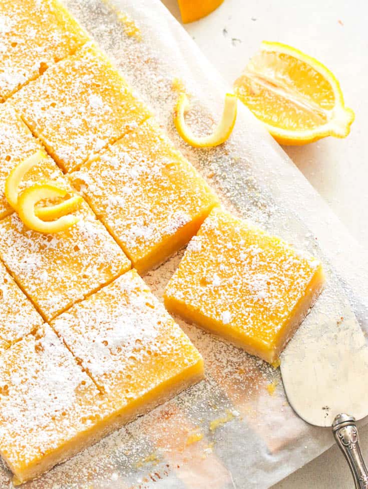 Lemon bars with powdered sugar on top and fresh lemon peels