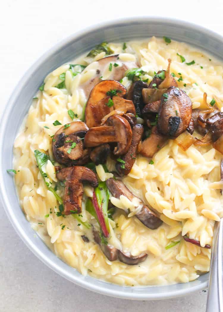 a gray bowl of Creamy Orzo topped with sauteed mushrooms and chopped parsley