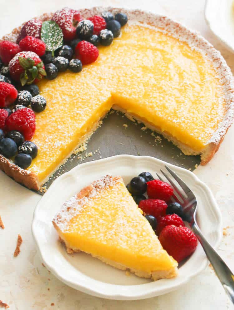 A slice of Lemon tart with fresh berries on the side
