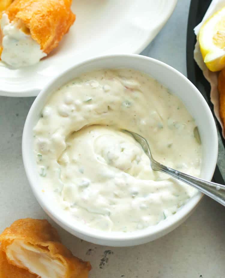 Homemade Tartar Sauce with sour cream and buttermilk in a white bowl with fried fish in the background