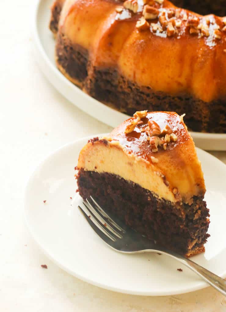 A slice of chocoflan served with the rest of the cake in the background