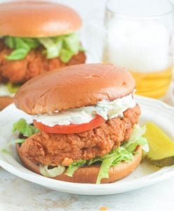 Insanely delicious chicken sandwich with tartar sauce on a white plate