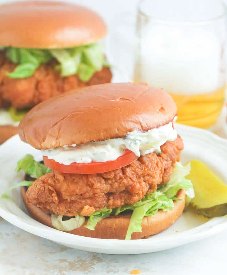 Insanely delicious chicken sandwich with tartar sauce on a white plate