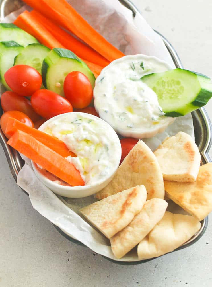 Tzatziki sauce served with pita bread, carrots, and cucumber slices