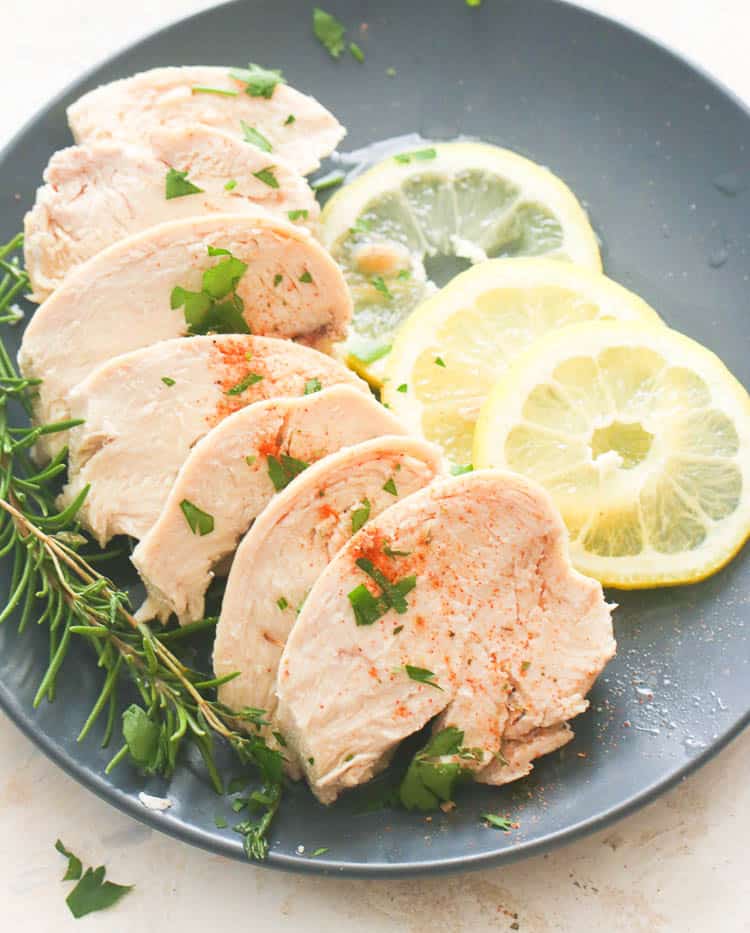 A Plate of Sliced Poached Chicken Served with Lemon Slices