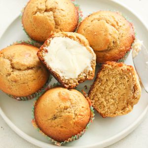 Banana Bread Muffins on a white plate and one is halved and buttered