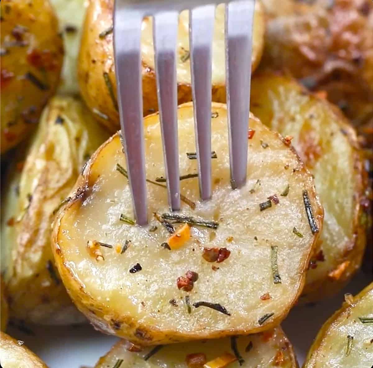 Forking into a tender roasted potato seasoned with garlic and rosemary.