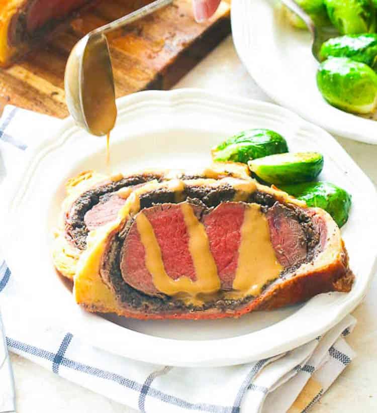 Drizzling a mustard cream sauce over Beef Wellington slices