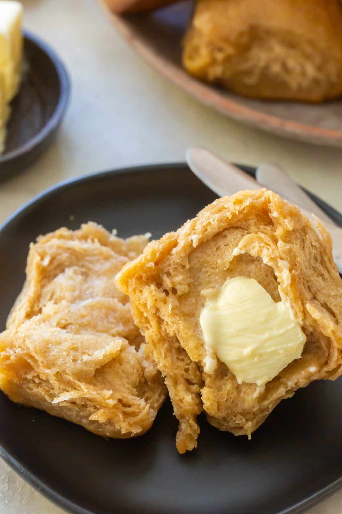 Close Up Shot of Honey Wheat Roll Slathered with Butter