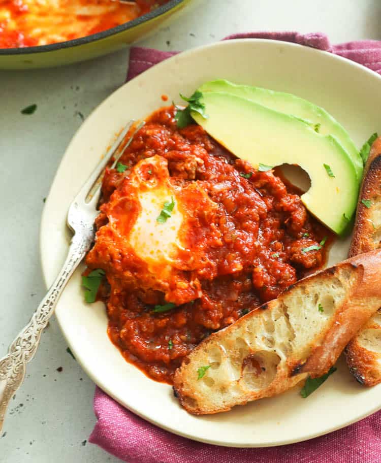 A plate of Eggs in Purgatory served with toast and avocado