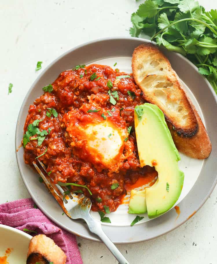 A plate of Eggs in Purgatory served with toast and avocado