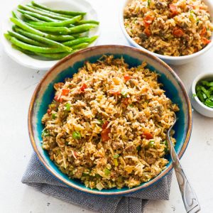 Flavorful Cajun Rice in a Blue Bowl with Sides of Greens