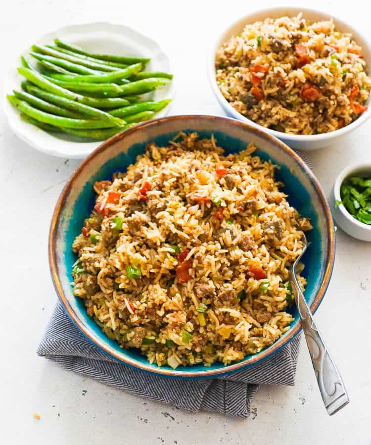 Flavorful Cajun Rice in a Blue Bowl with Sides of Greens