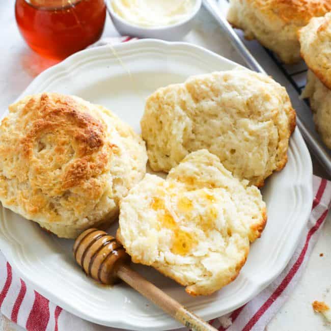 Biscuits with honey dipper on a white plate