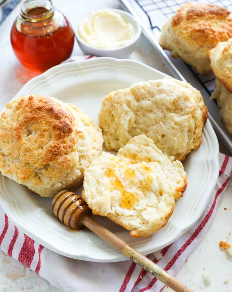 Cathead Biscuits with honey dipper on a white plate