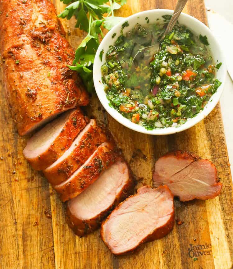 Smoked Pork Tenderloin on a wooden cutting board with chimichurri